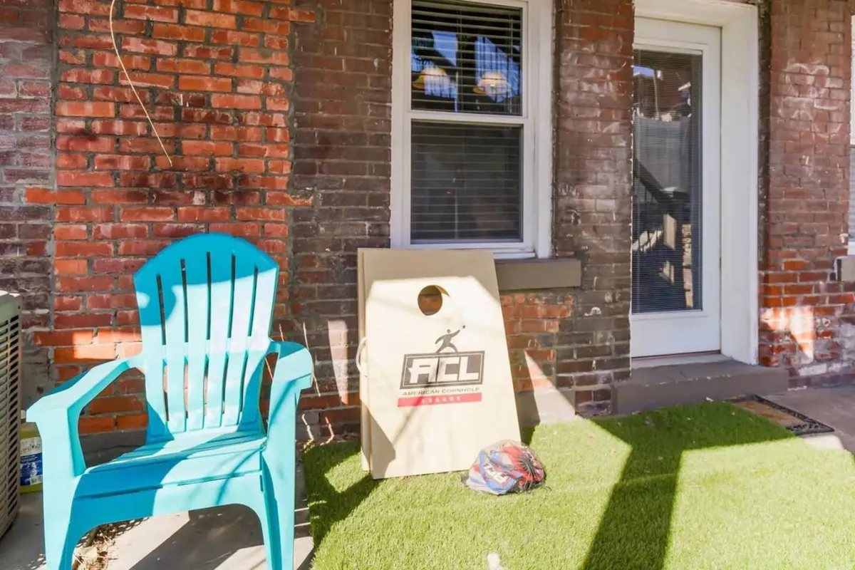A playful outdoor setup featuring a turquoise chair and cornhole board on green turf, suggesting opportunities for friendly competition, casual gatherings, and relaxed afternoons.