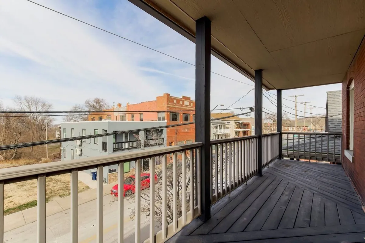 This image showcases a balcony with a sturdy railing, overlooking the surrounding buildings and offering a lively street view. The setting is casual and inviting, perfect for enjoying a coffee or soaking in the urban atmosphere after a day out exploring.